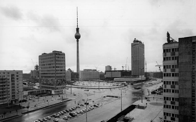 A cityscape showing tall buildings, a large tower in the center, and multiple vehicles on roads.